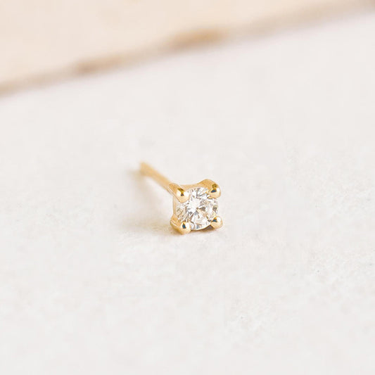 Close-up of a 14k Yellow Gold Diamond Stud Earring 2.5mm - Aria (Single) with a brilliant lab grown diamond on a light background
