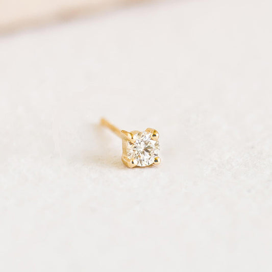 Close-up of a 14k Yellow Gold Diamond Stud Earring 3mm - Aria (Single) with a sparkling round diamond on a soft white surface
