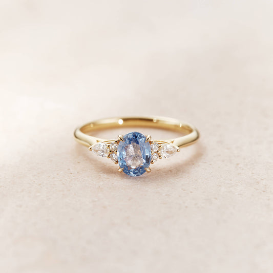 The ring features a Yellow Gold brilliant-cut round sapphire at its center, exhibiting a vivid light blue hue.