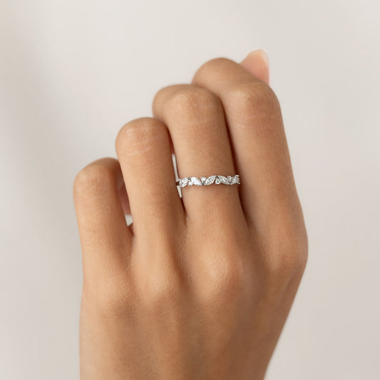 White gold ring with small diamonds on a hand against a neutral background