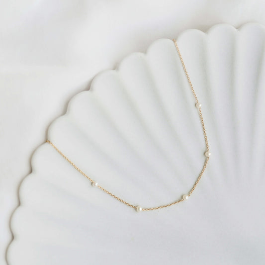 Pearl Station Necklace - Adara with freshwater pearls spaced on a gold vermeil chain on a white scalloped dish background