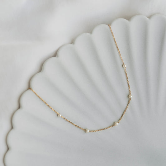 Pearl Station Necklace - Adara with freshwater pearls spaced on a gold vermeil chain on a white scalloped dish background