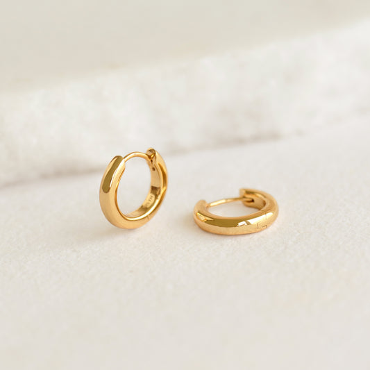Chunky Huggie Hoop Earrings - Dione in gold vermeil with a smooth, polished finish on a neutral background