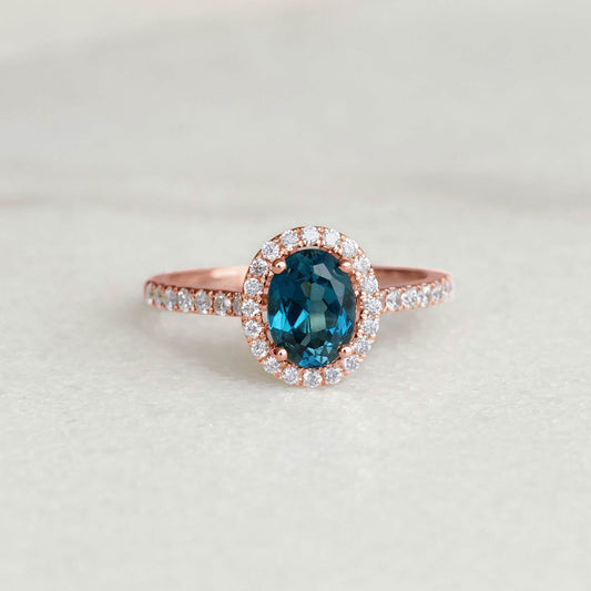 Oval London Blue Topaz Halo Ring Rose Gold - Suna with pavé diamonds surrounding the blue topaz on a neutral background
