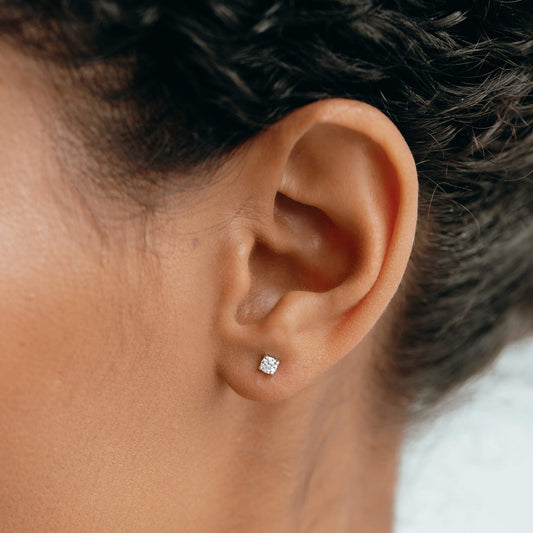 Close-up of an ear wearing 14k White Gold Diamond Stud Earrings 3mm - Aria with sparkling lab grown diamonds