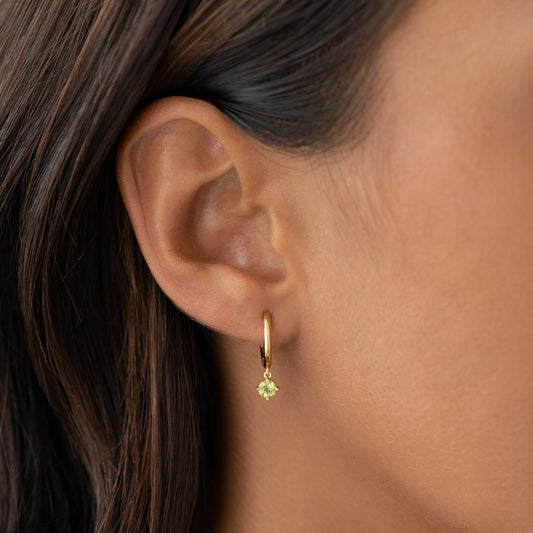 Close-up of ear wearing August Birthstone Drop Huggie Earrings - Olivine with gold vermeil and green gemstone drop