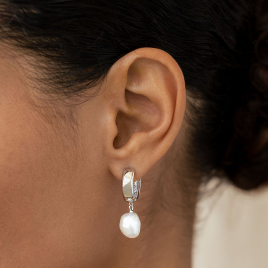 Close-up of an ear wearing Baroque Pearl Chunky Hoop Earrings Silver - Meredith with a freshwater pearl drop on a neutral background