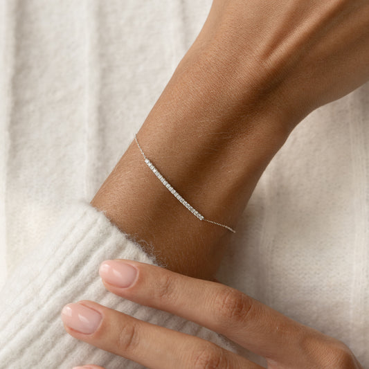 Close-up of a wrist wearing Diamond Curved Bar Bracelet White Gold - Vivienne with delicate diamonds on a fine chain
