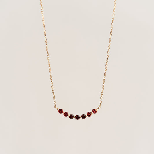 January Birthstone Necklace 14k Gold - Ombre Garnet with a delicate curved bar and gradient garnet stones on light background
