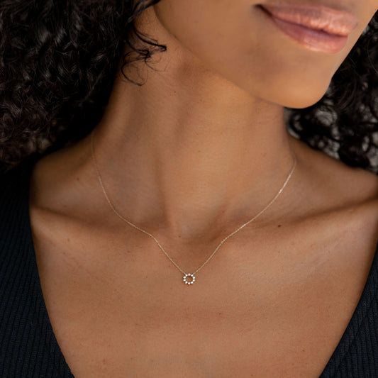 Close-up of a woman wearing the Diamond Sun Necklace 14k Gold - Lova with a black ribbed top on a neutral background