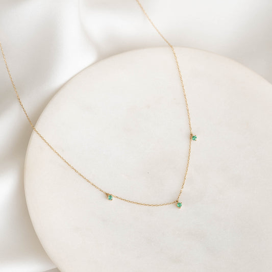 3-Emerald Necklace 14k Gold - Rosalia with three small emeralds on a delicate 14k gold chain displayed on a white surface