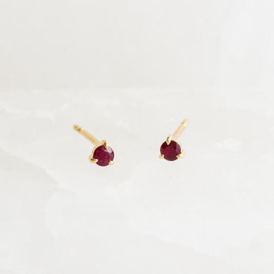 July Birthstone Stud Earrings 14k Gold - Ruby with small round ruby gemstones in three-prong yellow gold settings on white background