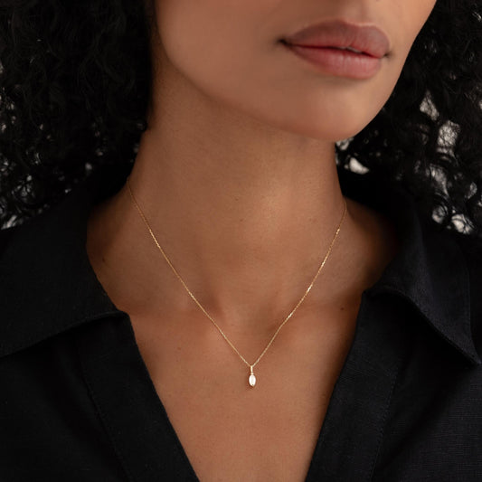 Close-up of a woman wearing the June Birthstone Pendant 14k Gold - Mother of Pearl on a delicate gold chain