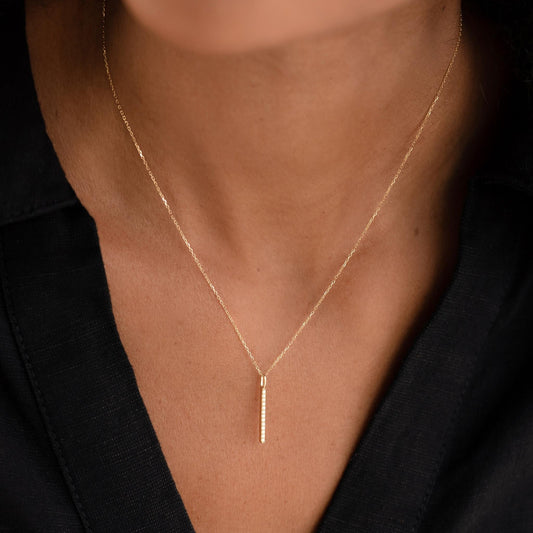 Close-up of a woman wearing Diamond Line Pendant 14k Gold on a delicate chain with a black top background