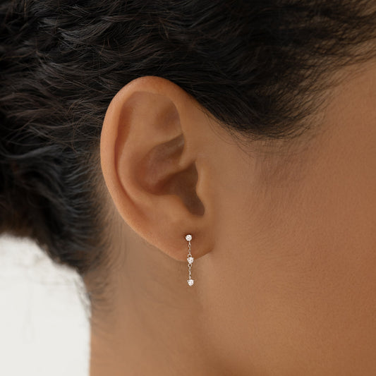 Close-up of an ear wearing Diamond Drop Earrings White Gold - Alessia with delicate diamonds on a fine white gold chain