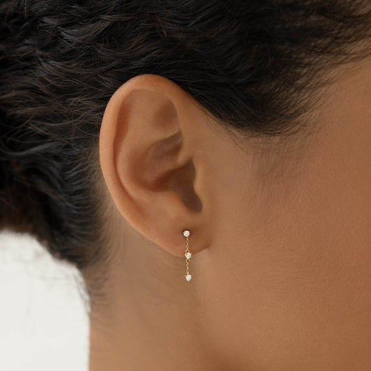 Close-up of an ear wearing Diamond Drop Earrings 14k Gold - Alessia featuring delicate diamonds on a gold chain
