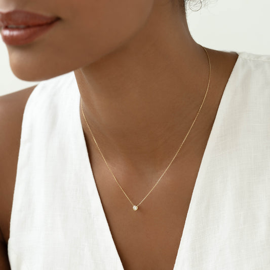 Close-up of woman wearing Bezel Set Lab Grown Diamond Necklace 14k Gold - Ulla with a white linen sleeveless top | 0.115 ct tw