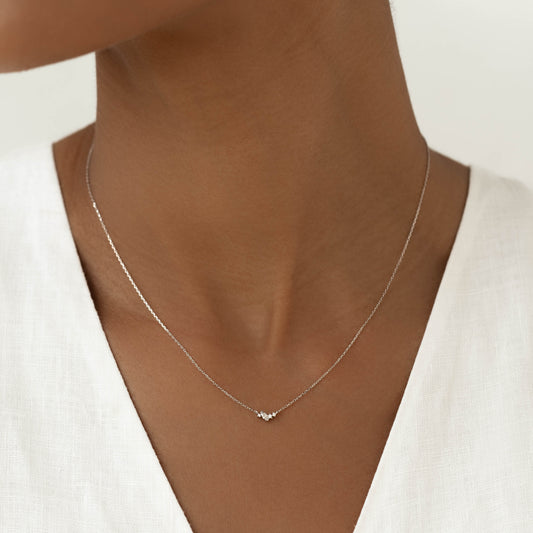 Close-up of a woman wearing the Diamond Cluster Necklace White Gold - Estrella with a white linen top