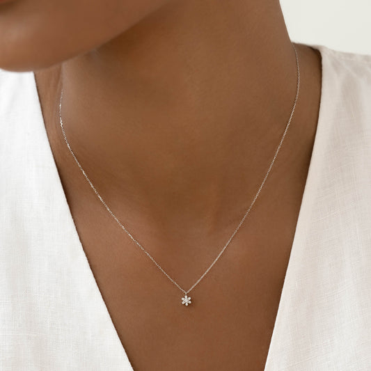 Close-up of a woman wearing the Diamond Flower Necklace White Gold - Haldis with a white linen top
