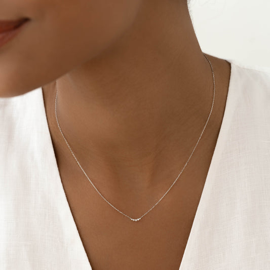 Close-up of woman wearing Diamond Curved Bar Necklace White Gold - Jemma with five small diamonds on a delicate chain