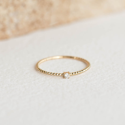 Diamond Beaded Ring 14k Gold - Natalie with a round diamond on a delicate gold beaded band on a neutral surface