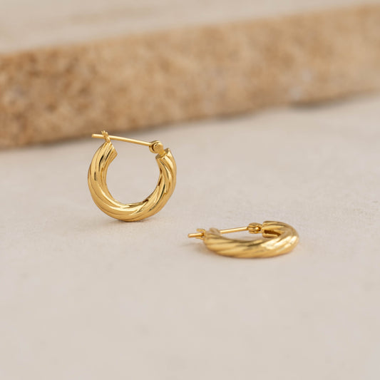 Braided Hoop Earrings - Helle displayed on a beige surface with a textured neutral background