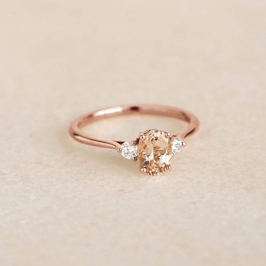 Morganite and Diamond Ring 14k Rose Gold - Kindra with oval morganite and two diamonds on a tapered gold band on soft background