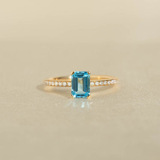 Baguette Swiss Blue Topaz and Diamond Ring 14k Gold - Safiya with a rectangular blue topaz and pavé diamond band on beige background