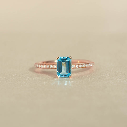 Baguette Swiss Blue Topaz and Diamond Ring Rose Gold - Safiya with baguette blue topaz and pavé diamonds on rose gold band on beige background