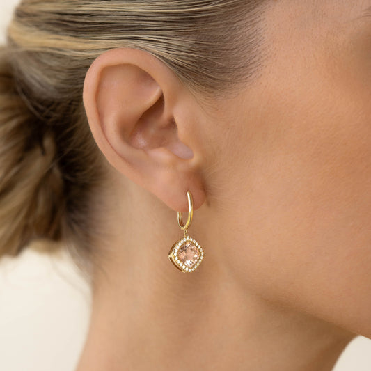 Close-up of a woman wearing Morganite and Diamond Halo Drop Earrings 14k Gold - Elvira on a beige background