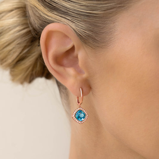 Close-up of an ear wearing Swiss Blue Topaz and Diamond Halo Drop Earrings Rose Gold - Elvira with blue gemstone and diamond halo detail