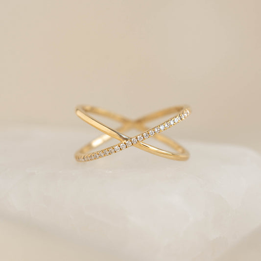 Close-up of Criss Cross Half Eternity Diamond Ring - Nuria in 14k gold with brilliant diamonds on a soft neutral background