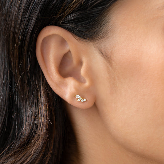 Close-up of a woman’s ear wearing Marquise Wing Earrings - Ava with gold vermeil and gemstone cluster on a neutral background