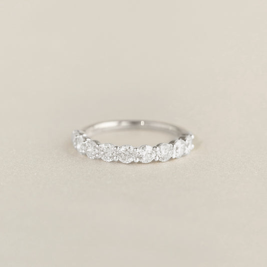 A delicate White Gold ring featuring a row of round cut diamonds set along the band, displayed on a soft beige background.