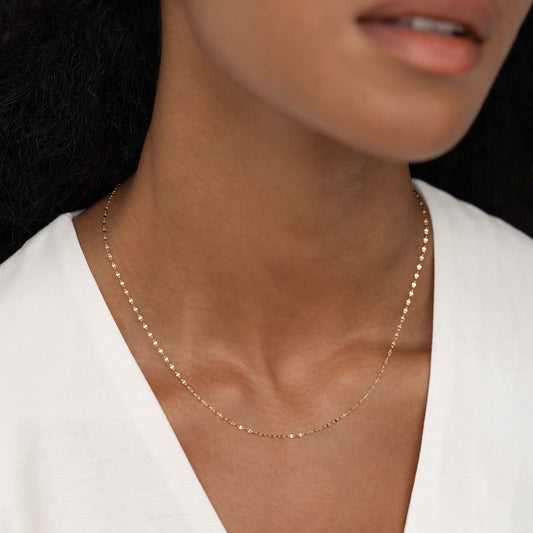 Close-up of a woman wearing Mirror Chain Necklace 14k Gold - Mira with delicate petal-shaped links on bare neck