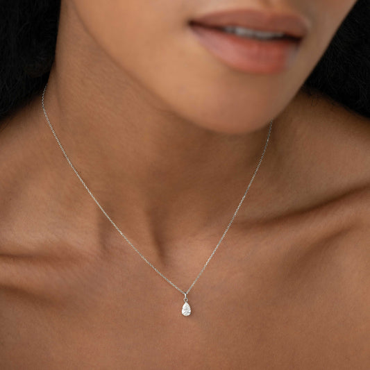 Close-up of a woman wearing the Pear Cut Diamond Pendant Necklace White Gold - Oline on a delicate 14k chain