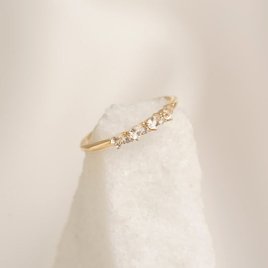 Close-up of April Birthstone Pear Ring 14k Gold - White Topaz and Diamond on textured white stone background