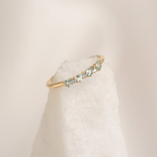 Close-up of March Birthstone Pear Ring 14k Gold - Swiss Blue Topaz and Diamond on a white textured stone background