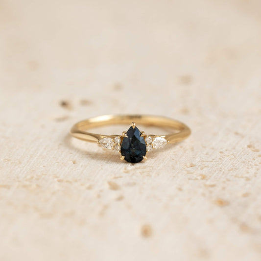 A close-up photograph displays a delicate yellow Gold ring centered against a soft, textured beige background.