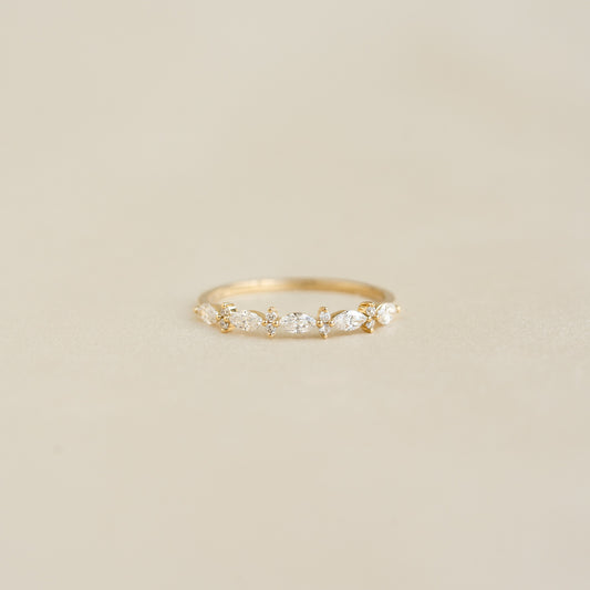 Close-up of Marquise and Round Diamond Ring - Aurelia with marquise and round diamonds on 14k yellow gold band on beige background