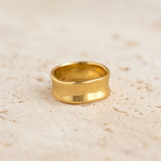 Close-up of a gold vermeil Wide Organic Ring - Essie with smooth curved edges on a textured beige surface