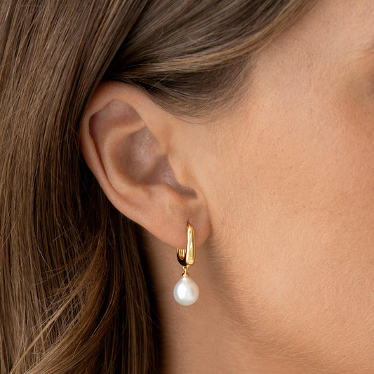 Close-up of a woman's ear wearing Pearl Drop Hoop Earrings - Maeve with gold vermeil and freshwater pearl drop detail