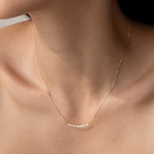 Close-up of a woman wearing the Marquise and Round Diamond Necklace 14k Gold - Noelia with delicate diamonds on a gold chain
