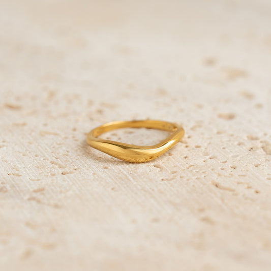 Close-up of a gold vermeil Organic Wavy Ring - Nyssa with smooth curves on a textured beige surface