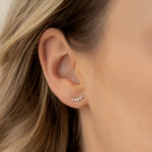Close-up of an ear wearing Diamond Climber Stud Earrings White Gold - Rhea with curved row of sparkling diamonds