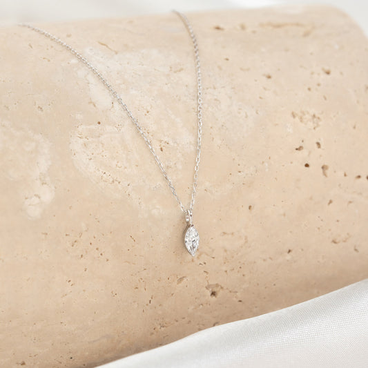Close-up of a marquise diamond pendant on a delicate chain from the Marquise Diamond Necklace White Gold - Violetta displayed on stone