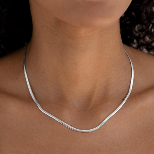 Close-up of a woman wearing a sleek Snake Chain Necklace Silver with a natural skin tone background