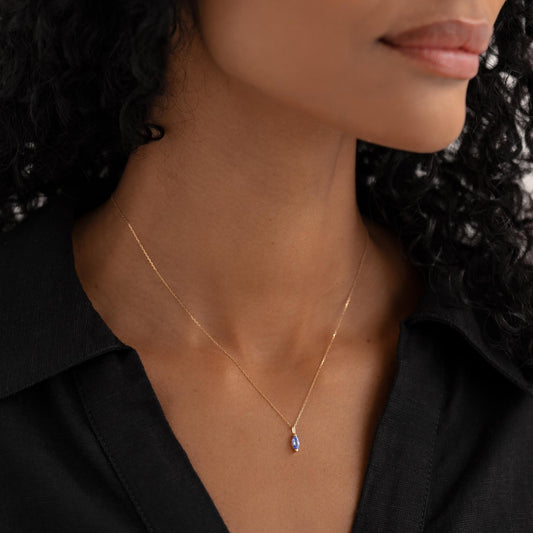 Close-up of a woman wearing December Birthstone Pendant 14k Gold - Tanzanite with a black collared shirt
