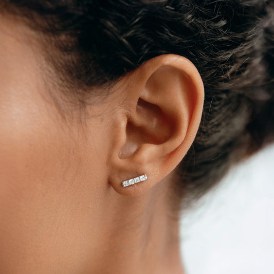 Close-up of a woman's ear wearing 14k White Gold Diamond Bar Stud Earrings - Lucia with four sparkling diamonds