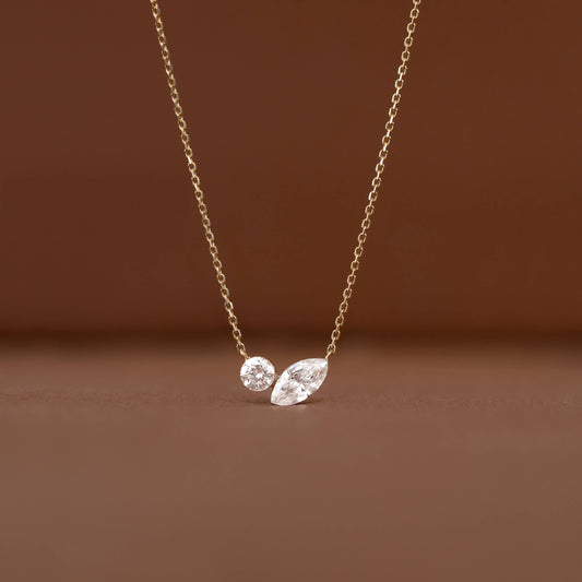 Delicate Gold chain necklace displayed against a warm brown background, featuring two diamond pendants.